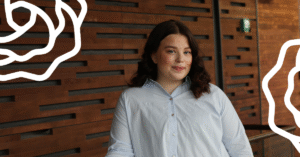 Nainen vaaleassa kauluspaidassa nojaa kaiteeseen ja hymyilee.